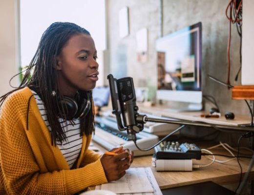 Cheerful African woman working on radio station, talking on microphone in talk show